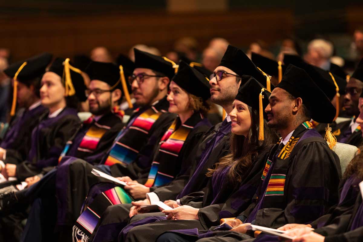 A group of graduates pose in their caps and gowns.